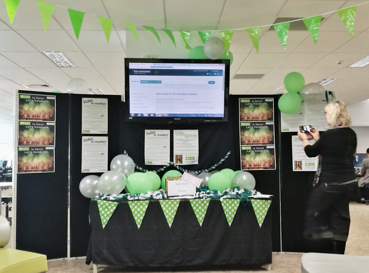Go-live day at Toi Ohomai a large booth display set up at the Toi Ohomai Library with green balloons and bunting, with signs about the new Koha LMS system