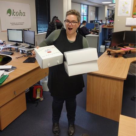 Kathryn Tyree of Catalyst IT in the Wellington Koha office, holding boxes of donuts that were gifted from Toi Ohomai on go-live day